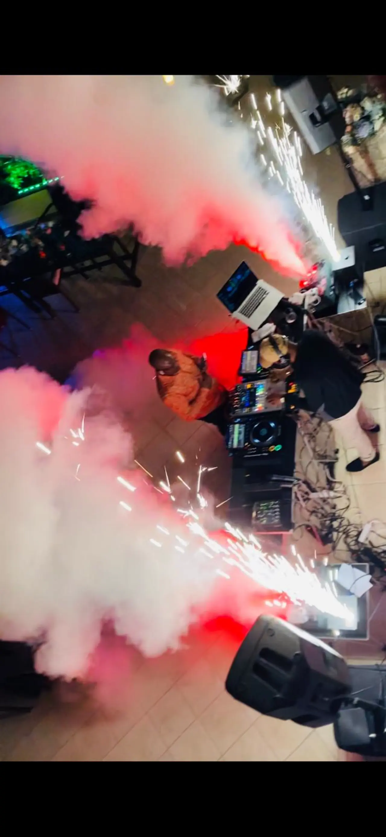 DJ playing in a smoke with flashlights around.